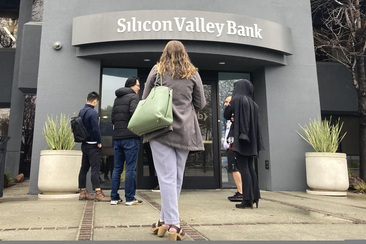 FILE - People stand outside a Silicon Valley Bank branch in Santa Clara, Calif., on March 10, 2023. California's bank regulator was too slow to see the growing risks at Silicon Valley Bank and did not act forcefully enough to get the bank to fix its problems, the regulator found in its own report issued Monday, May 8. (AP Photo/Jeff Chiu, File)