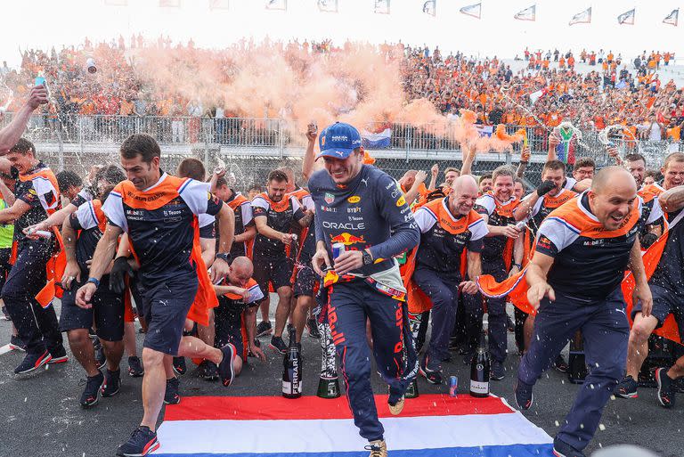 Max Verstappen se lanza en carrera después de celebrar la victoria del Gran Premio de los Países Bajos con los integrantes del equipo Red Bull Racing; de fondo, la multitud le ofrece color al festejo del campeón