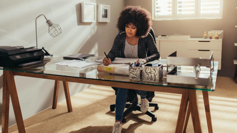 African woman working on new building plans while sitting at her desk.