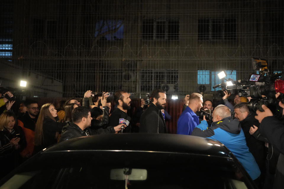 Andrew Tate, center left, and his brother Tristan, center, stand outside a police detention facility in Bucharest, Romania, after their release from prison on Friday March 31, 2023. An official on Friday said Tate, the divisive internet personality who has spent months in a Romanian jail on suspicion of organized crime and human trafficking, has won an appeal to replace his detention with house arrest. (AP Photo/Andreea Alexandru)