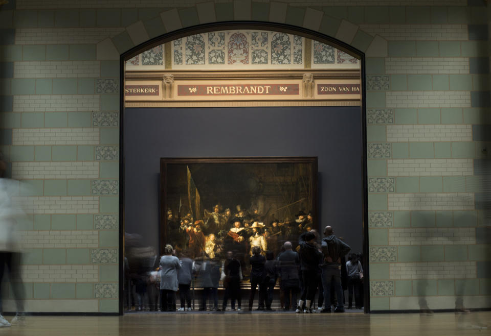 FILE - Visitors admire Rembrandt's Night Watch (1642), part of an exhibition of the all the Rijksmuseum's Rembrandts in Amsterdam, Netherlands, Wednesday, Feb. 13, 2019. The Netherlands' national museum is planning to re-stretch Rembrandt van Rijn's huge painting "The Night Watch," to get rid of deformations in its top left corner, the Rijksmuseum announced Wednesday. (AP Photo/Peter Dejong, File)