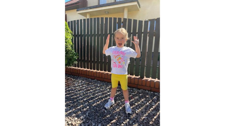 Ola and James Jordan's daughter Ella holds her hands up in front of the family home in Poland