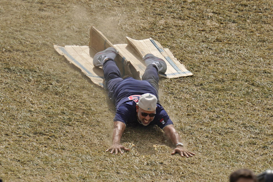 Boston Red Sox manager Alex Cora slides of a piece of cardboard half way down the hill in the outfield of Lamade Stadium during a visit to the Little League World Series in South Williamsport, Pa., Sunday, Aug. 21, 2022. The Red Sox will play the Baltimore Orioles in the Little League Classic on Sunday Night Baseball. (AP Photo/Gene J. Puskar)