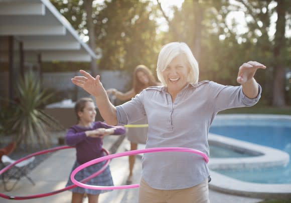 A senior woman uses a hoola hoop.