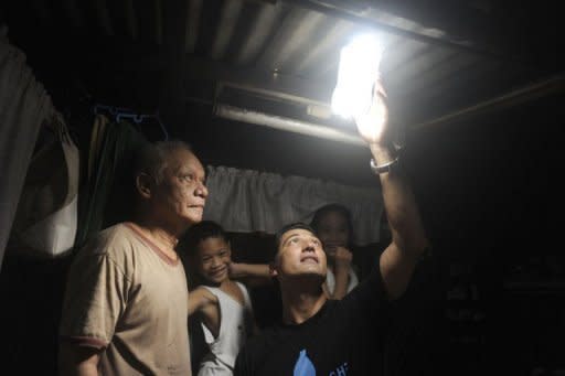 Illac Diaz (R) and Siplicio Mondas inspect a solar light bottle installed by Philippine soldiers in a shanty town in Manila. With the help of some plastic bottles plus a social media campaign, Diaz is aiming to help a million poor people in a year