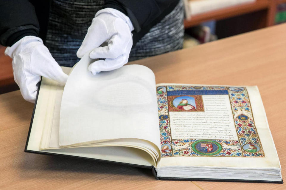 A librarian displays a unique 15th century ornamented manuscript on parchment in a library in Torun, Poland, on Monday, Feb. 14, 2022. Local authorities and officials in central Poland are protesting government plans to offer Hungary a unique 15th century ornamented manuscript that is the most precious item of a library in Torun. A lawmaker with Poland's right-wing ruling party has proposed legislation that would allow the government to take possession of the manuscript and offer it to the government of Prime Minister Viktor Orban. (AP Photo/Andrzej Goinski)