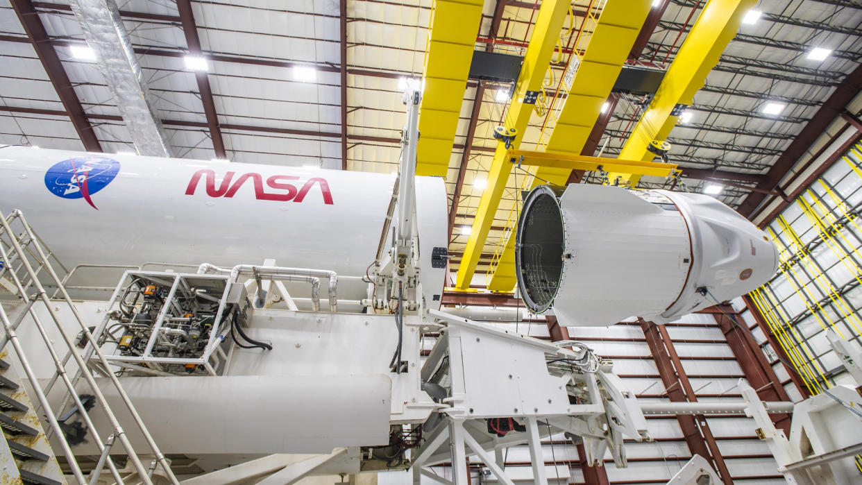  A white SpaceX Endeavour Dragon capsule is mated to its Falcon 9 rocket with NASA logos on white backgrounds. 