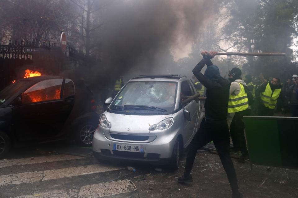 Hooded demonstrators smash a car during a demonstration Saturday, Dec.1, 2018 in Paris. Protesters angry about rising taxes clashed with French police for a third straight weekend and over 100 were arrested after pockets of demonstrators built barricades in the middle of streets in central Paris, lit fires and threw rocks at officers Saturday. (AP Photo/Thibault Camus)