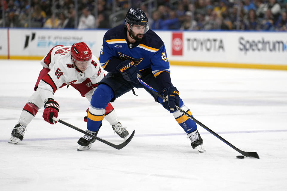 St. Louis Blues' Nick Leddy (4) brings the puck down the ice as Carolina Hurricanes' Jake Guentzel (59) defends during the second period of an NHL hockey game Friday, April 12, 2024, in St. Louis. (AP Photo/Jeff Roberson)