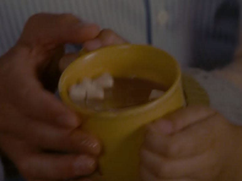 hands holding a yellow mug of hot cocoa in the holiday
