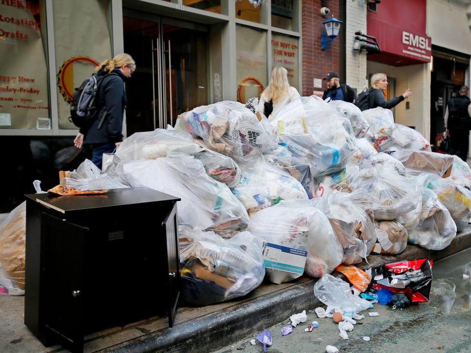 People make their way past trash bags in New York City.