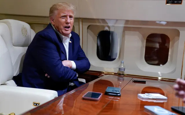 Mr Trump speaks with reporters while in flight on his plane after the campaign rally at Waco - AP