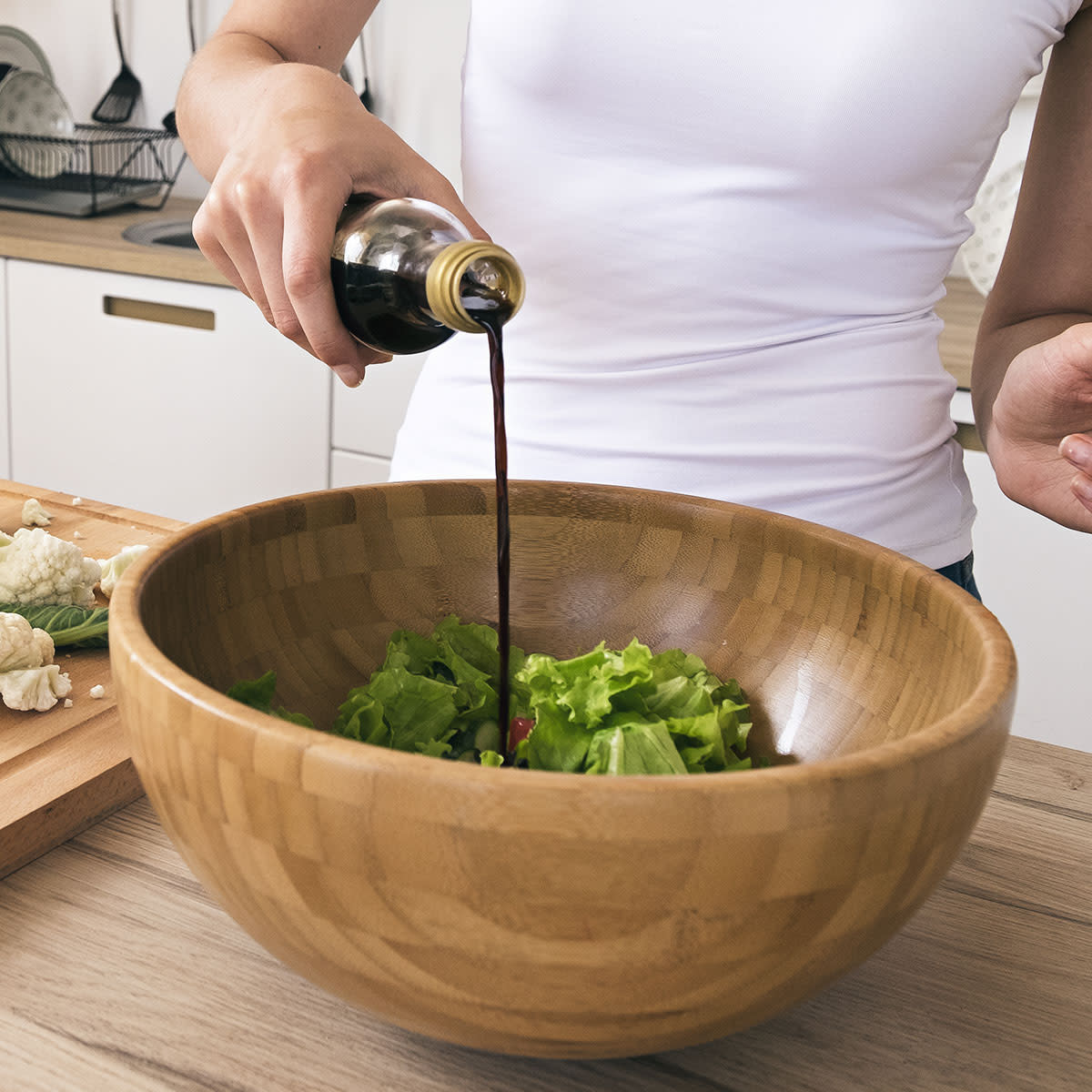 woman building salad in large bowl