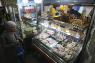 A woman walks past a butcher in a market near Algiers, Tuesday, March 26, 2024. As Muslim-majority countries reckon with increased demand throughout Islam's holy month of Ramadan, is trying to flood new markets with pantry staples to stave off shortages that can cause prices to rise. (AP Photo/Anis Belghoul)