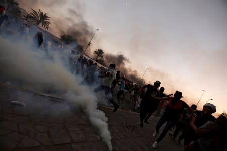 Demonstrators disperse as Iraqi security forces use tear gas during a protest after the lifting of the curfew, following four days of nationwide anti-government protests that turned violent, in Baghdad