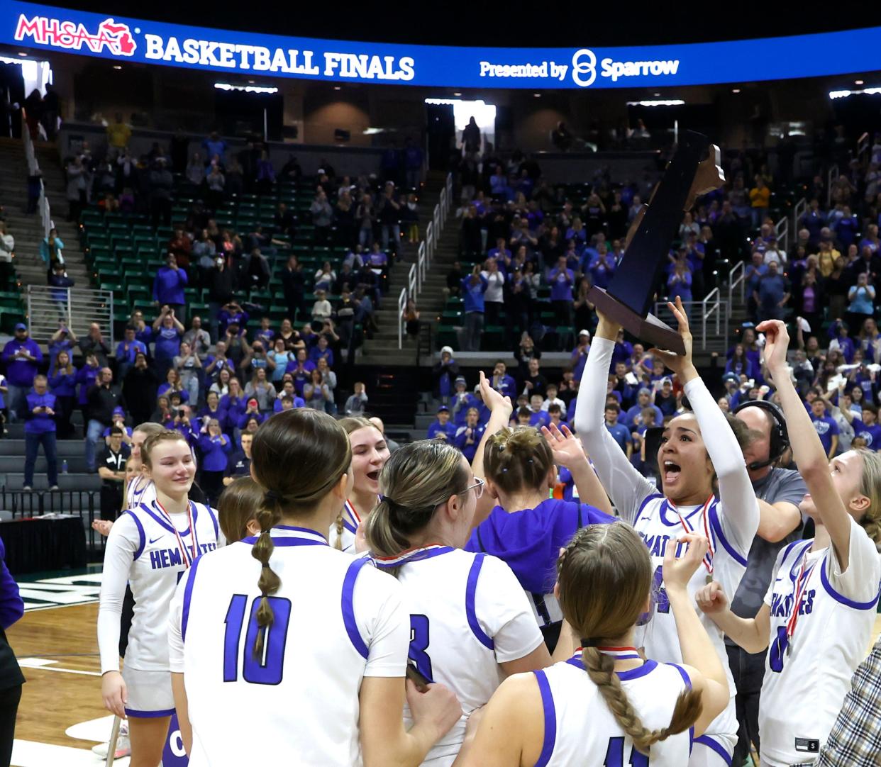 Ishpeming players celebrate with their championship trophy after defeating Kingston 73-54 in the MHSAA Division 4 girls basketball finals at Breslin Center in East Lansing on Saturday, March 23, 2024.