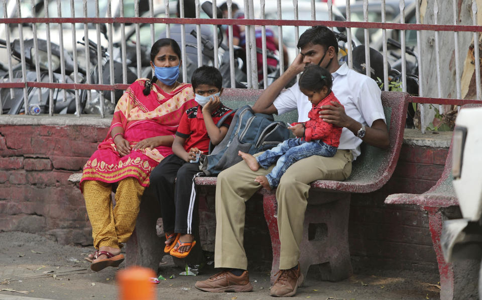 Indians wearing masks wait for transport outside a hospital in Jammu, India, Tuesday, June 23, 2020. India has been recording about 15,000 new infections each day, and some states Tuesday were considering fresh lockdown measures to try to halt the spread of the virus in the nation of more than 1.3 billion. (AP Photo/Channi Anand)