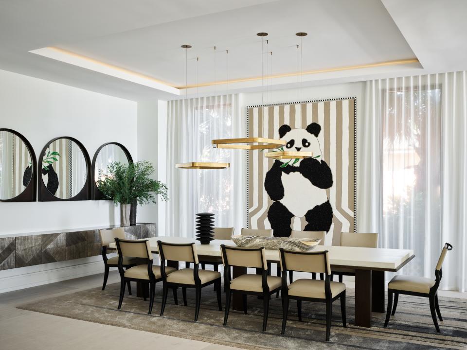 The dining room’s focal point is a whimsical panda painting by Robert Pruitt. Wecselman designed the sideboard and mirrors for the space, and the table and chairs are by Liaigre. Pendant lights by Henge hang overhead.