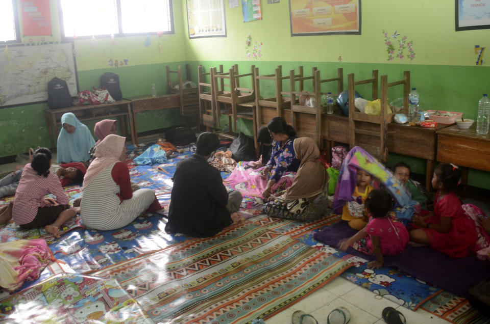 People rest at a school turned into temporary shelter for those affected by the eruption of Mount Semeru, in Lumajang, East Java, Indonesia, Sunday, Dec. 4, 2022. Indonesia's highest volcano on its most densely populated island released searing gas clouds and rivers of lava Sunday in its latest eruption. (AP Photo/Hendra Permana)