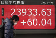 A man walks past an electronic stock board showing Japan's Nikkei 225 index at a securities firm in Tokyo, Friday, Feb. 7, 2020. Asian stock markets have retreated following a surge driven by a Chinese tariff cut on U.S. imports. (AP Photo/Eugene Hoshiko)