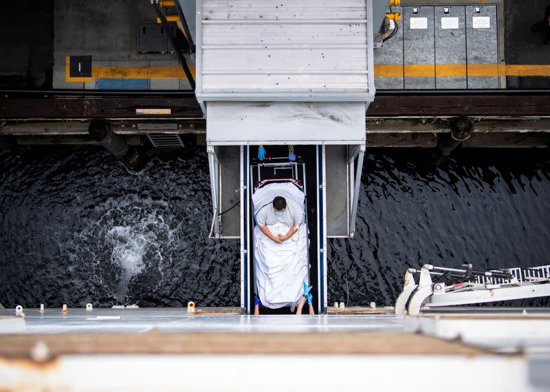 Sailors transport a patient across the brow to be admitted aboard the hospital ship USNS Mercy