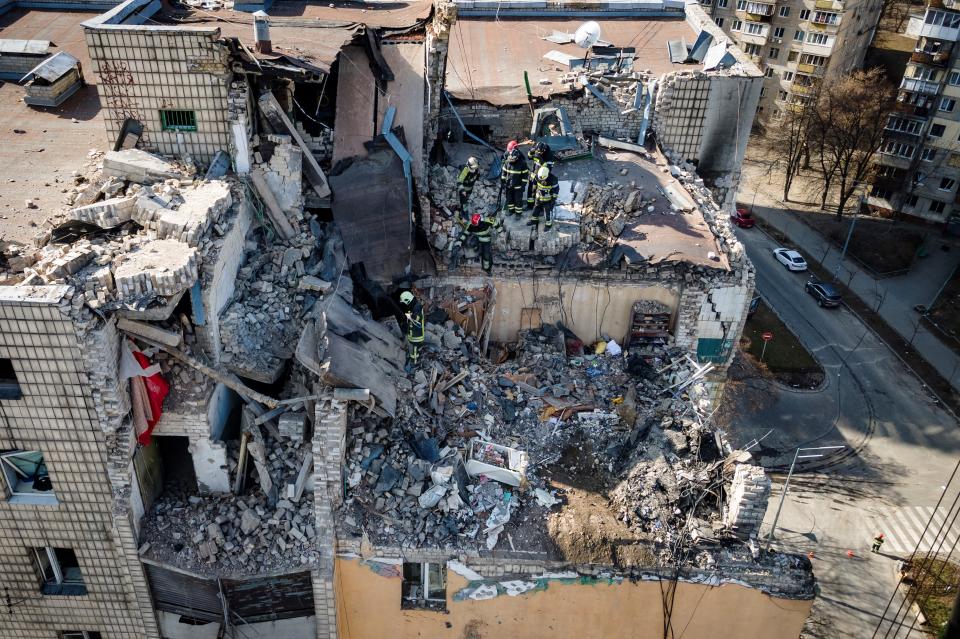 An aerial view shows firemen working in the rubble of a residential building which was hit by the debris from a downed rocket in Kyiv on March 17, 2022. - One person was killed and three injured when debris from a downed rocket hit a Kyiv apartment block, as Russian forces press in on the capital, emergency services said. Russian troops trying to encircle Kyiv have launched early morning strikes on the city for several successive days, putting traumatised residents further on edge. (Photo by FADEL SENNA / AFP) (Photo by FADEL SENNA/AFP via Getty Images)