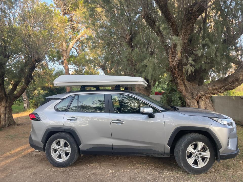 silver crossover rental car with a luggage storage on top in a forested area of crete