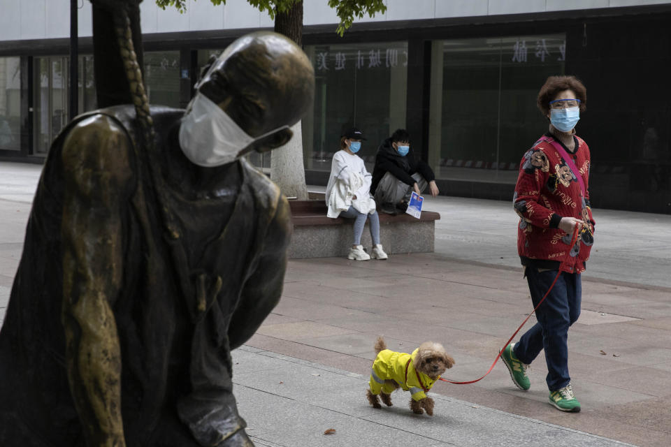 A woman walks her dog on the streets of Wuhan (Ng Han Guan/AP)