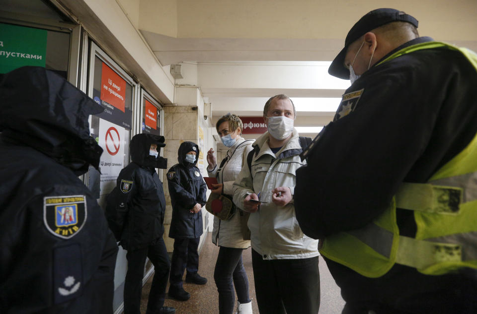 Policemen check the passenger passes at a subway station entrance in Kyiv, Ukraine, Monday, April 5, 2021. Authorities in Kyiv introduced tighter lockdown restrictions following a recent spike in virus cases. (AP Photo/Efrem Lukatsky)