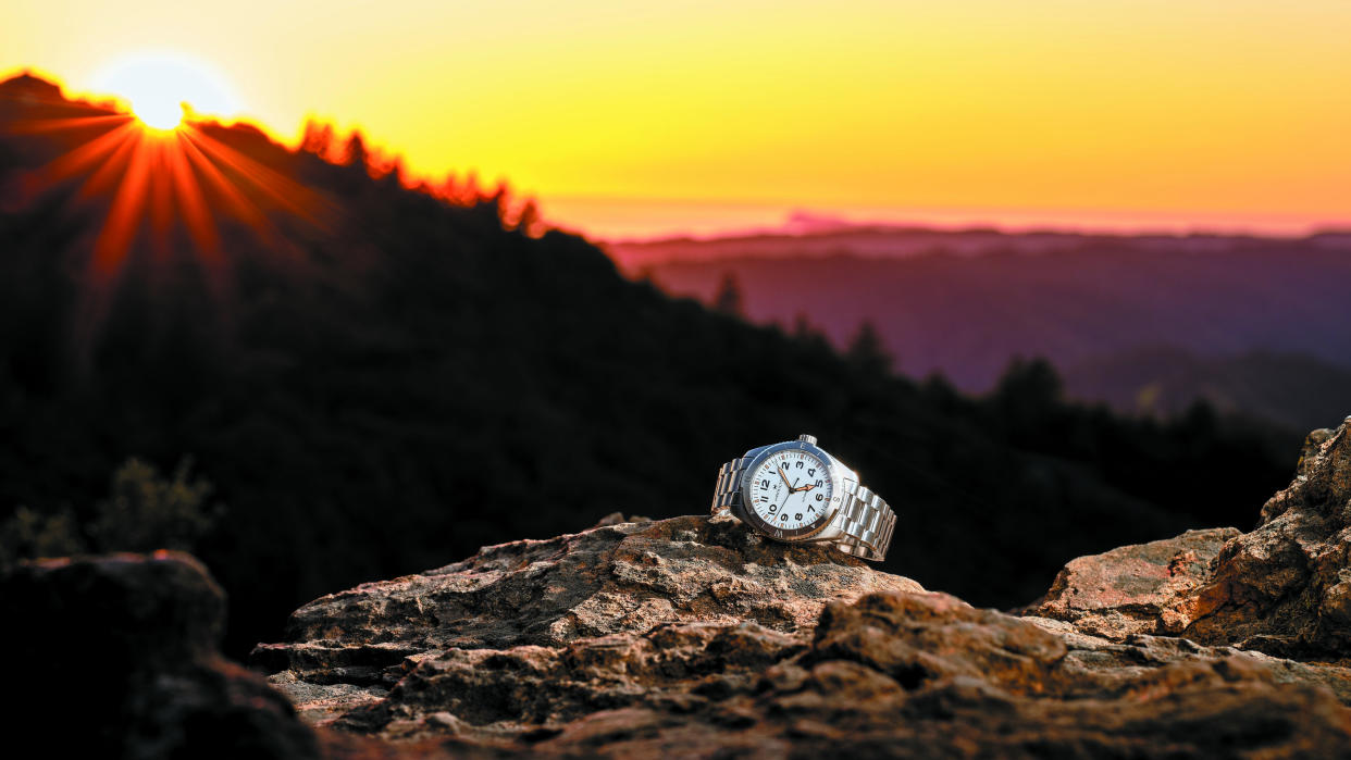  The Hamilton Khaki Field Expedition on a rock in front of a sunset. 