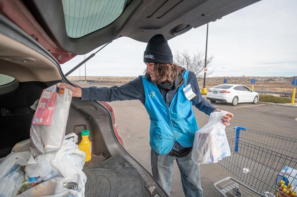 Abaddon Romero loads plastic bags filled with groceries into a customer's vehicle at the Northside Walmart in Pueblo on Tuesday, Dec. 27, 2022.