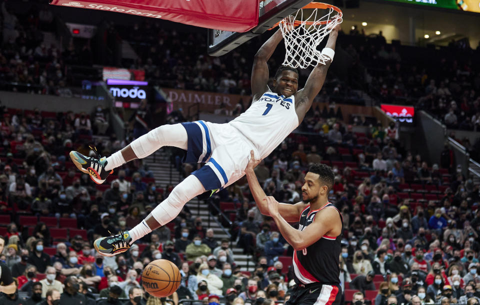 Minnesota Timberwolves forward Anthony Edwards (1) dunks over Portland Trail Blazers guard CJ McCollum during the second half of an NBA basketball game in Portland, Ore., Tuesday, Jan. 25, 2022. (AP Photo/Craig Mitchelldyer)