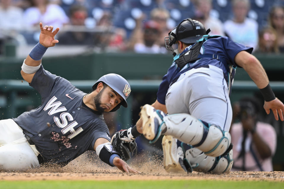 Washington Nationals' Keibert Ruiz, left, beats the tag of Seattle Mariners catcher Cal Raleigh at home plate during the seventh inning of a baseball game, Saturday, May 25, 2024, in Washington. (AP Photo/John McDonnell)