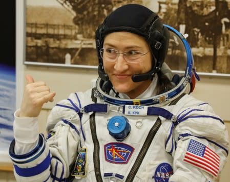 The International Space Station (ISS) crew member Christina Koch of the U.S. gestures after donning space suits shortly before their launch at the Baikonur Cosmodrome