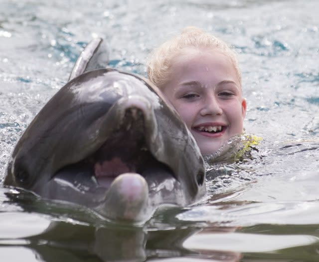 Jaz Ellis, 8, From Poole, Dorset, swims with a dolphin during the Dreamflight visit to Discovery Cove in Orlando, Florida