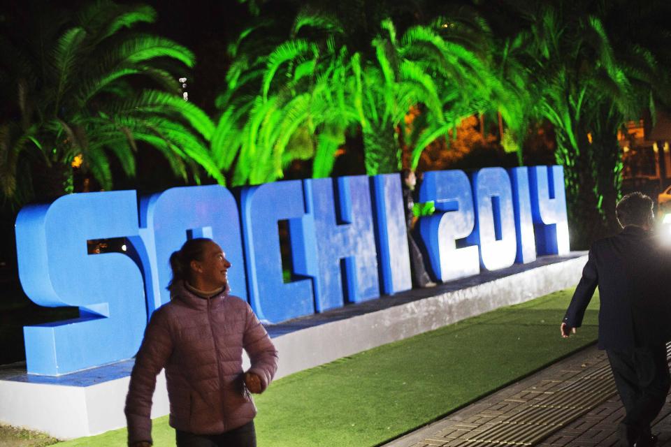 Pedestrians pass a sign reading "Sochi 2014," Saturday, Feb. 15, 2014, in central Sochi, Russia, home of the 2014 Winter Olympics. (AP Photo/David Goldman)