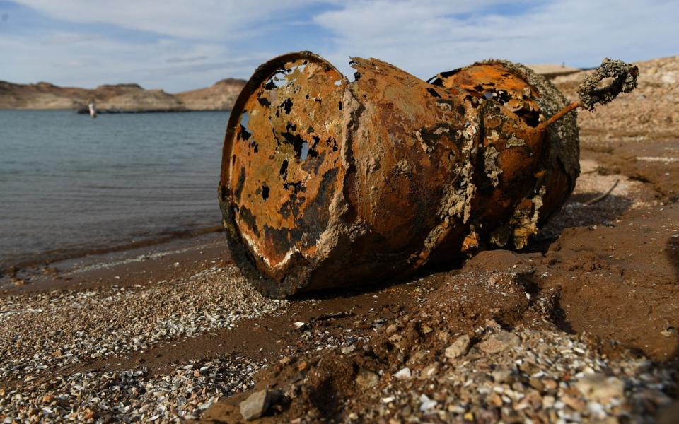 A rusted metal barrel, near the location of where a different barrel was found containing a human body, sits exposed on shore during low water levels due to the western drought at the Lake Mead Marina on the Colorado River in Boulder City, Nevada on May 5, 2022. - A worsening drought has revealed a four-decade-old body dumped in Lake Mead, police said May 2, 2022, warning that falling water levels would lead to the uncovering of more corpses. Boaters on Lake Mead near Las Vegas discovered a corroded barrel with its sinister contents during a weekend pleasure trip. (Photo by Patrick T. FALLON / AFP) (Photo by PATRICK T. FALLON/AFP via Getty Images) - PATRICK T. FALLON/AFP via Getty Images