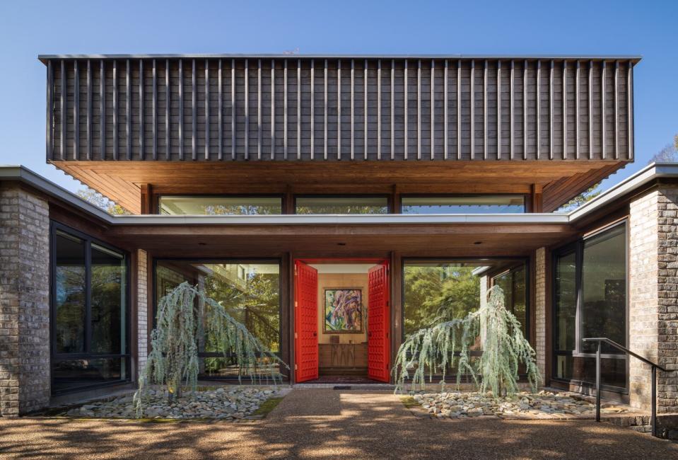 Homeowner Amy Clark requested the restored front doors be painted red like an Eero Saarinen womb chair. The "hat" roof's original shingles and metal soffits were removed and replaced with Kebony wood.