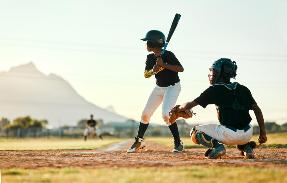 Young baseball players on a field, a batter at home plate, and a catcher in position, with a game in progress