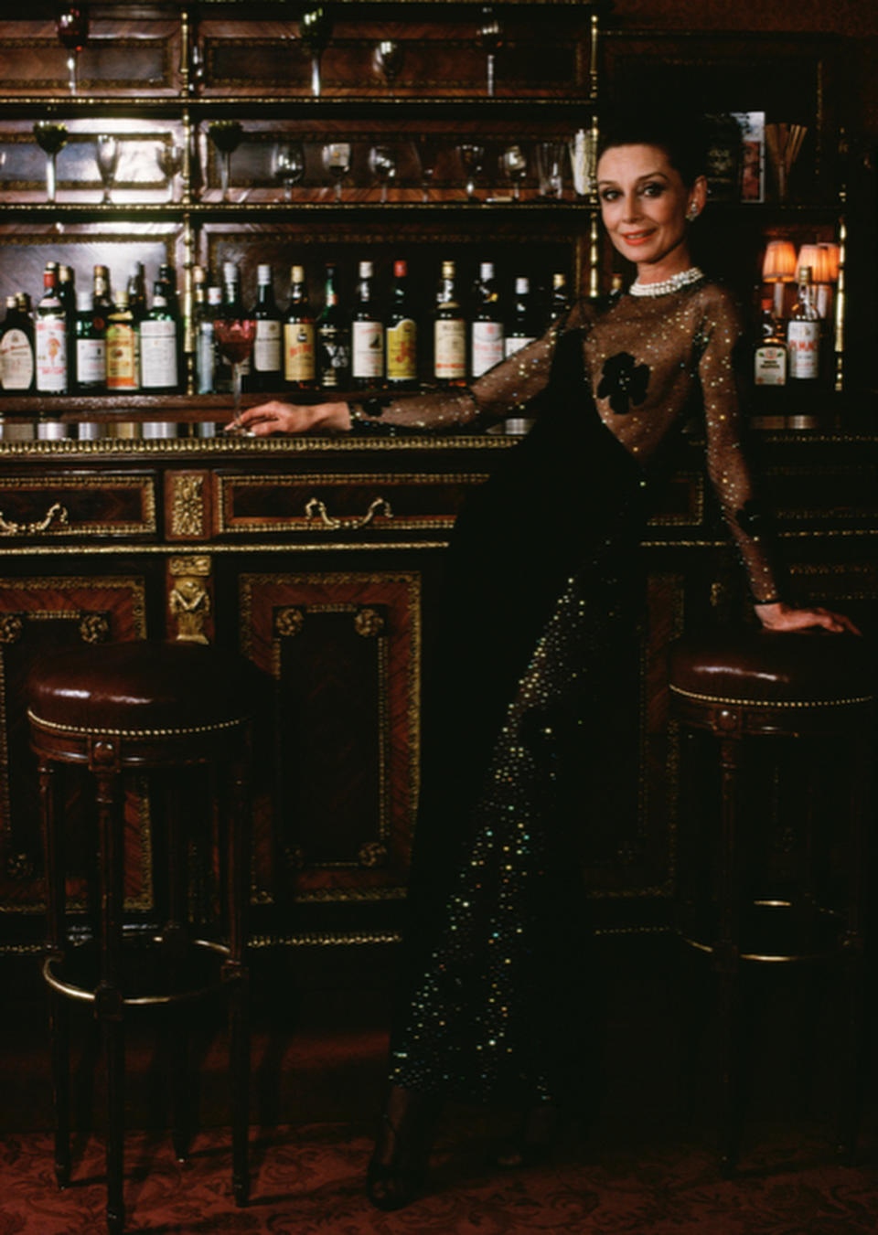 Hepburn wearing Givenchy, in the upstairs bar at Maxim’s restaurant.