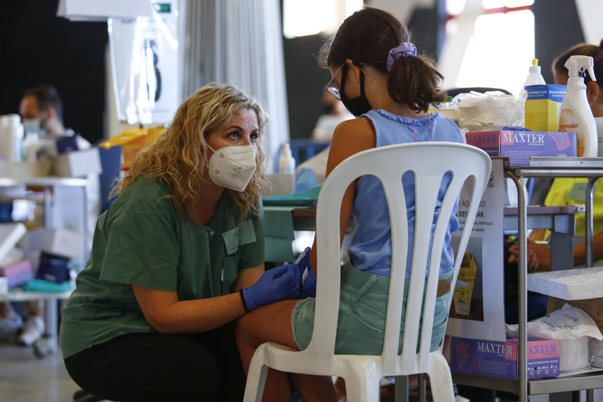 A nurse with a syringe calms a girl while the COVID-19 vaccination goes on for children and young people in Granada, Spain on September 03, 2021.
 (Photo by Álex Cámara/NurPhoto via Getty Images)