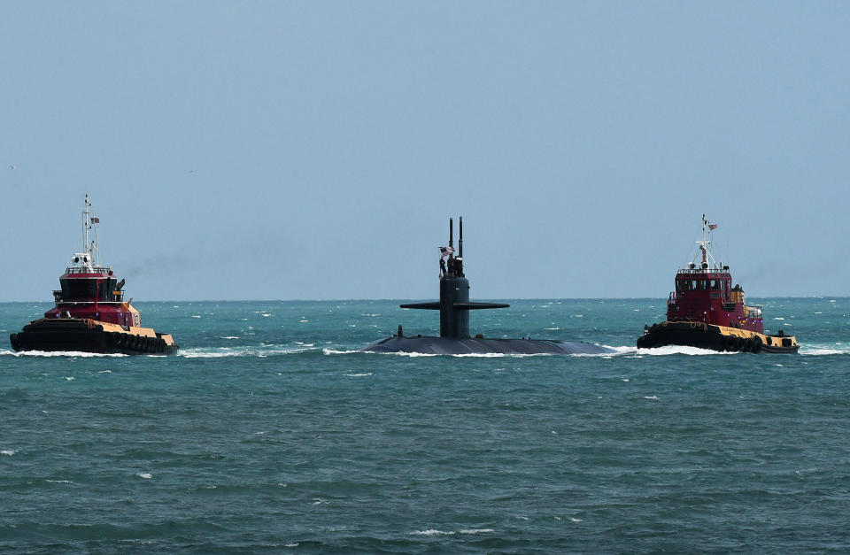 A Virginia-class nuclear powered submarine surrounded by two boats off the coast of Florida.