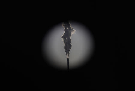 A heating station chimney is seen through a hole in a steel wall at a construction site in Beijing December 2, 2014. Awareness of the dangers of Beijing's skies is on the rise, thanks to growing data on its air quality. REUTERS/Kim Kyung-Hoon