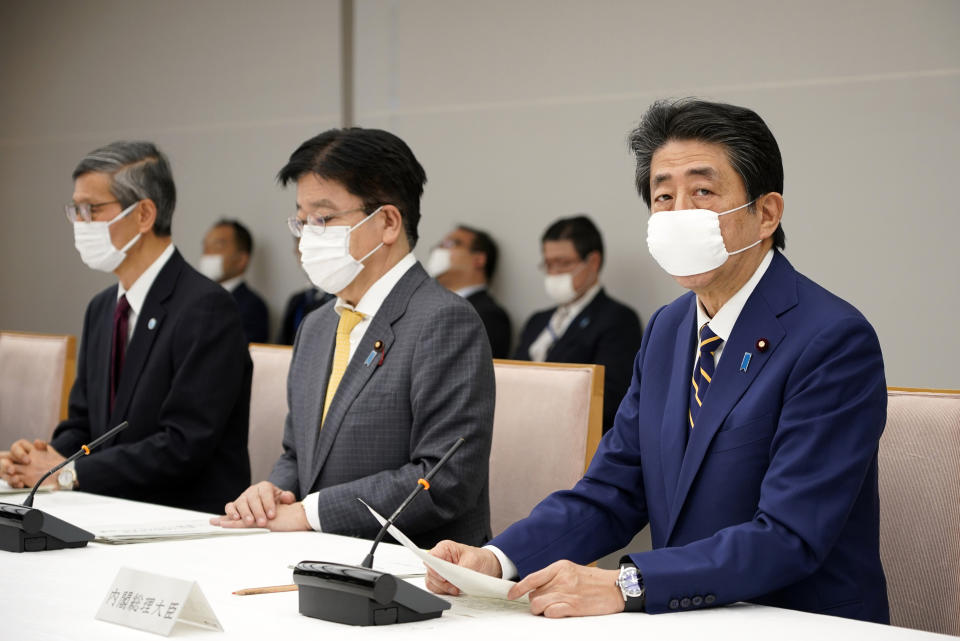 Japanese Prime Minister Shinzo Abe, right, declares a state of emergency during a meeting of the task force against the coronavirus at the his official residence in Tokyo, Tuesday, April 7, 2020. Abe declared a state of emergency for Tokyo and six other prefectures to ramp up defenses against the spread of the coronavirus. (Franck Robichon/Pool Photo via AP)