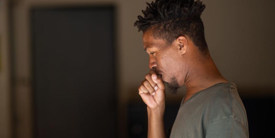 side view portrait of young male with green eyes and rasta hair coughing