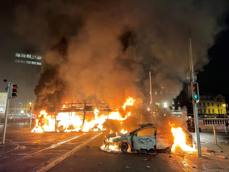 A bus and car on fire in Dublin’s city centre after violent protests erupted following a stabbing attack (PA)