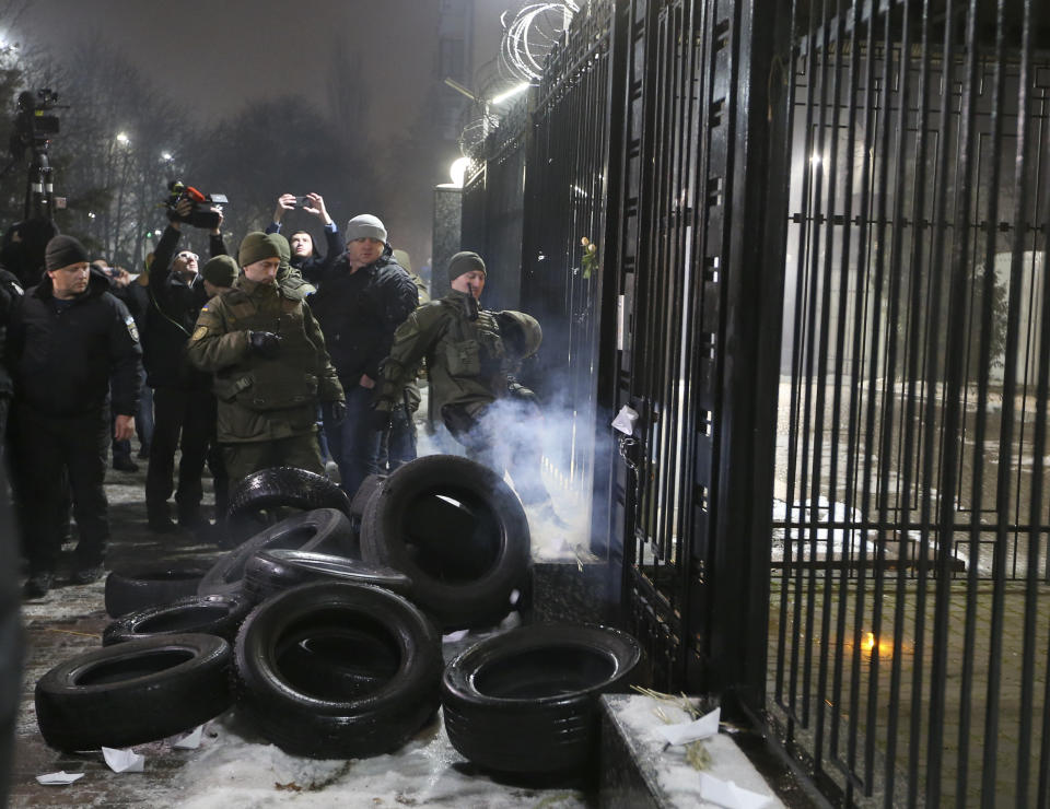 An Ukrainian police officer to put out a fire set as a barricade of tires by protesters during a rally in front of the embassy of Russia in Kiev, Ukraine, Sunday, Nov 25, 2018. Russia's coast guard opened fire on and seized three of Ukraine's vessels Sunday, wounding two crew members, after a tense standoff in the Black Sea near the Crimean Peninsula, the Ukrainian navy said. (AP Photo/Efrem Lukatsky)