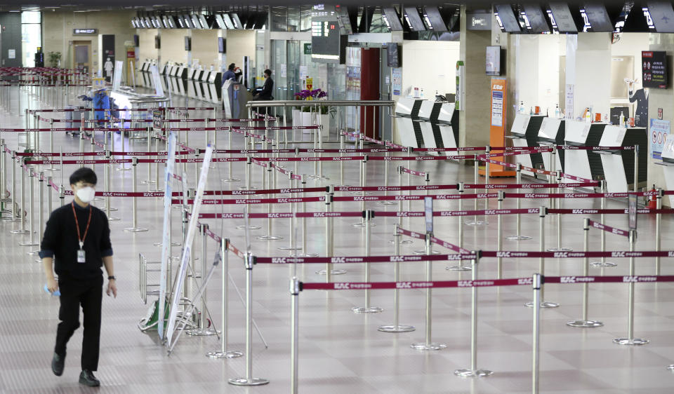 A man wearing a face mask passes by empty ticket counters at the Daegu Airport in Daegu, South Korea, Monday, Feb. 24, 2020. South Korea reported another large jump in new virus cases Monday a day after the the president called for "unprecedented, powerful" steps to combat the outbreak that is increasingly confounding attempts to stop the spread. (KimHyun-tae/Yonhap via AP)