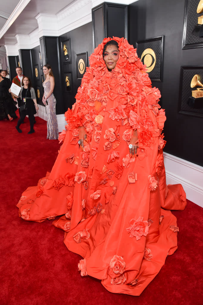 Lizzo covered head to toe in orange cape covered with roses. 