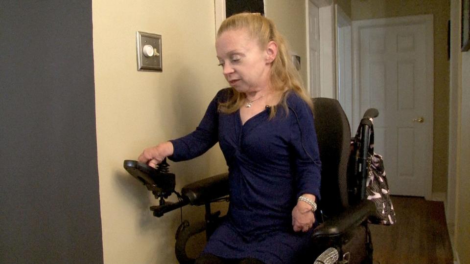 Kelly Boyd raises her wheelchair to reach a light switch in her Hamilton Township home Wednesday, November 1, 2023. She spoke about the delays that the disability community faces when their wheelchair needs repairs.